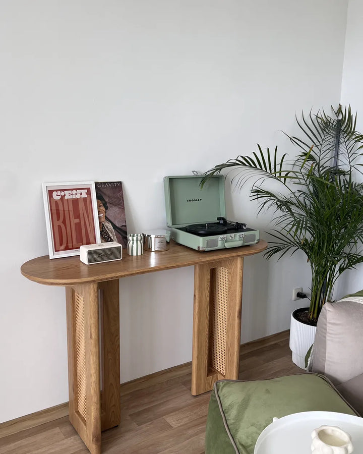 Wooden side table with a record player, speakers, and decorative items against a white wall.