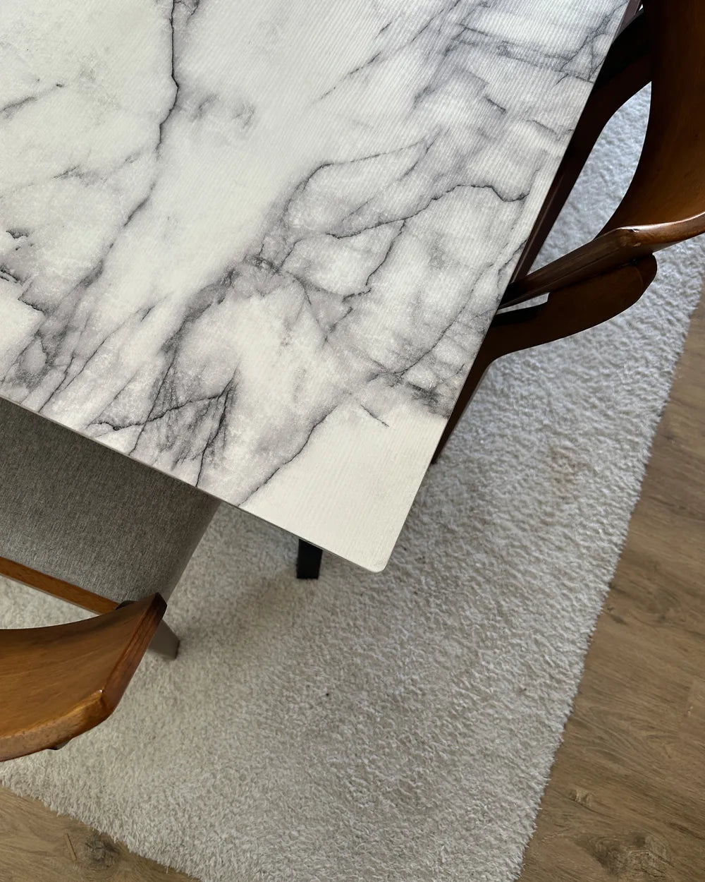 Marble-patterned table with wooden chairs on a textured rug