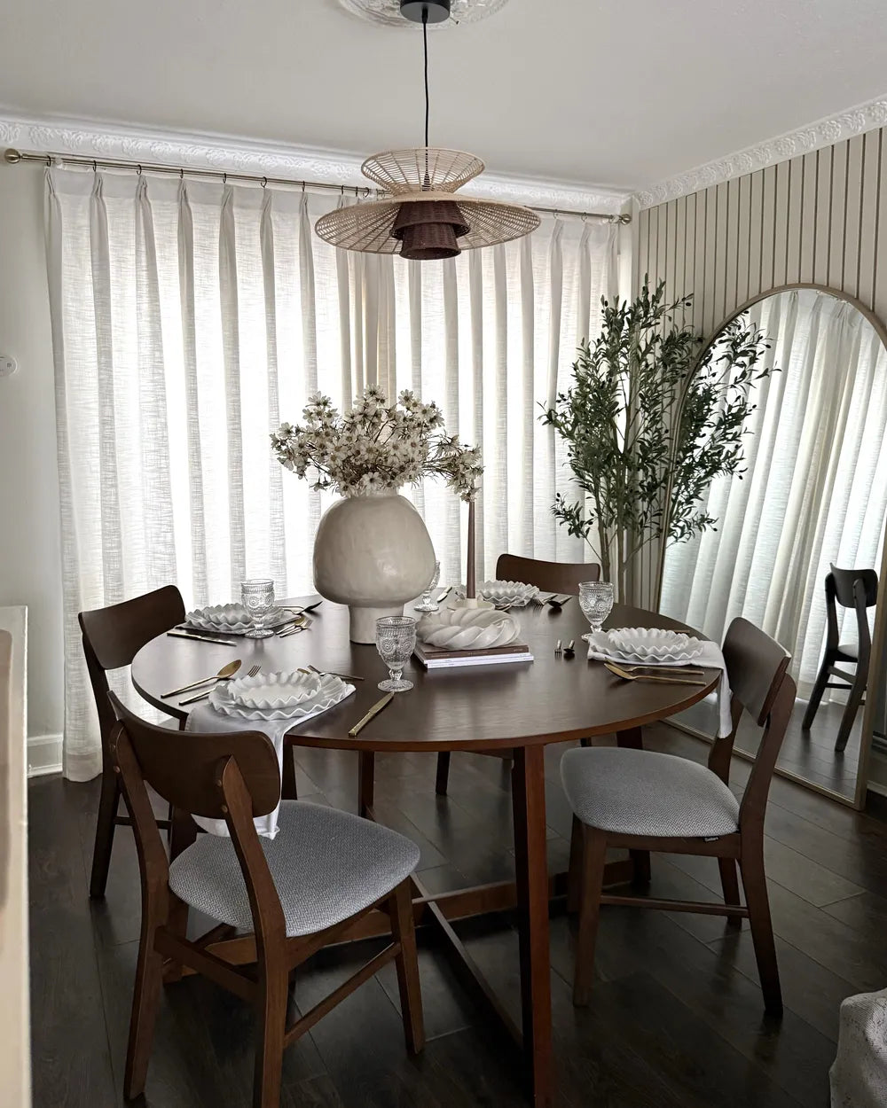 Dining room with a round wooden table and chairs, featuring a chandelier and decorative elements.