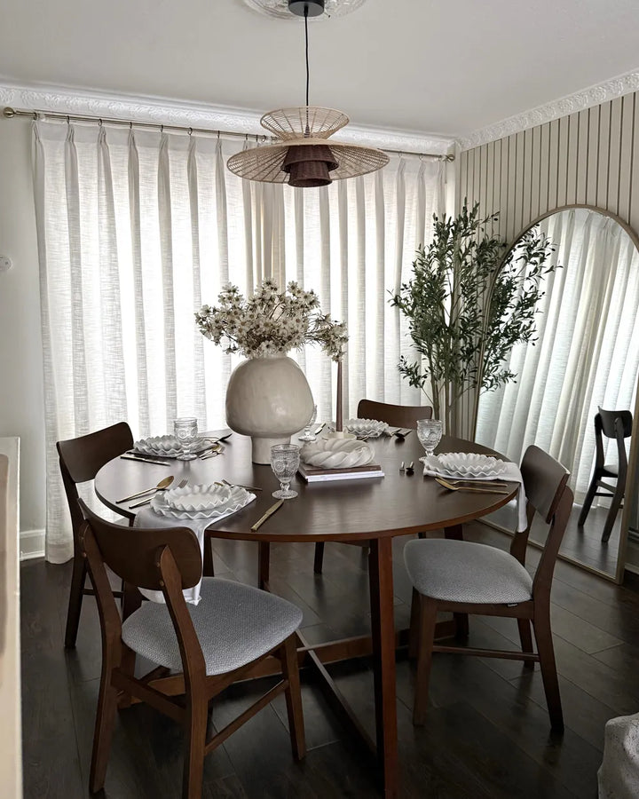 Dining room with a round wooden table and chairs, featuring a chandelier and decorative elements.