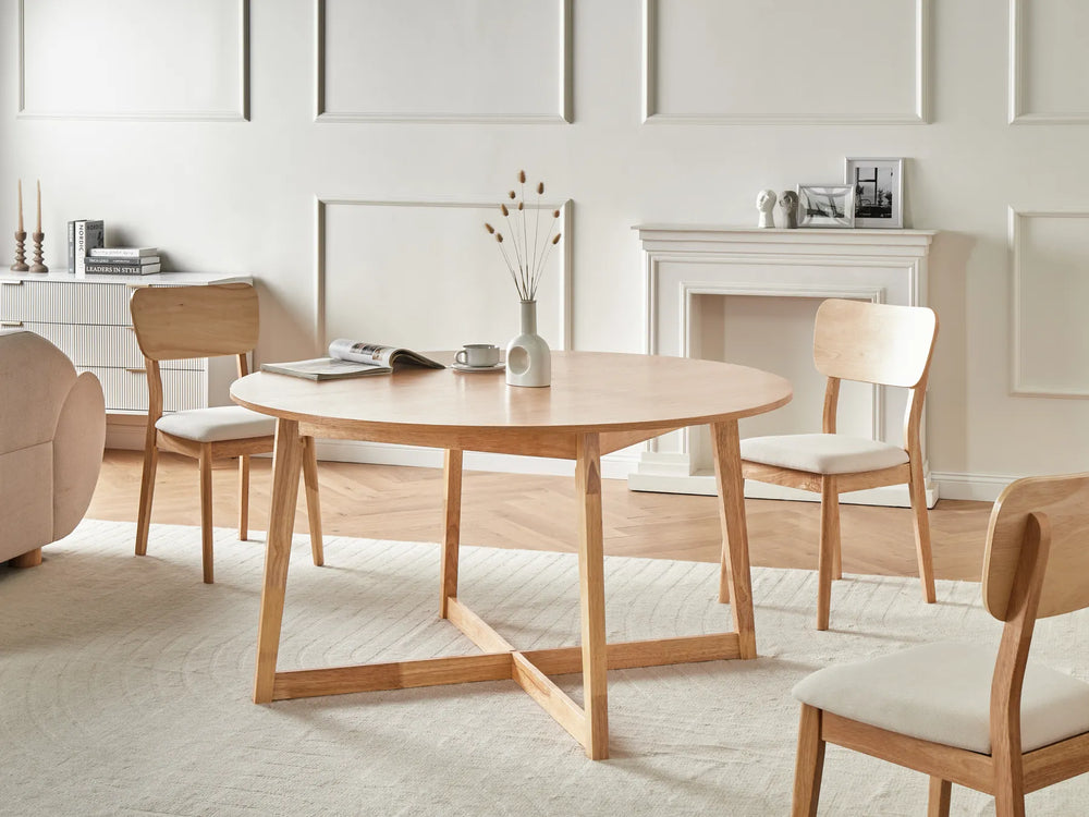Wooden dining table with chairs in a bright room with a fireplace.