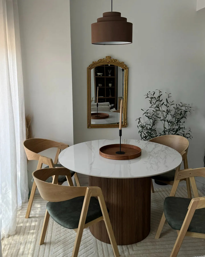 Dining room with a round marble table and wooden chairs.