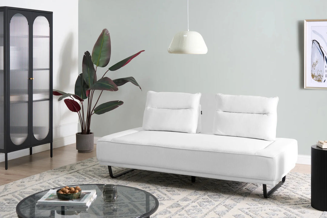 White sofa in a living room with a plant, coffee table, and side table.