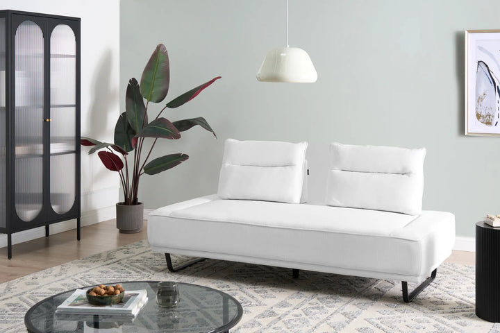 White sofa in a living room with a plant, coffee table, and side table.